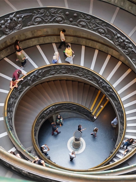 Spiral staircase in Vatican Museums, Rome, with visitors descending.