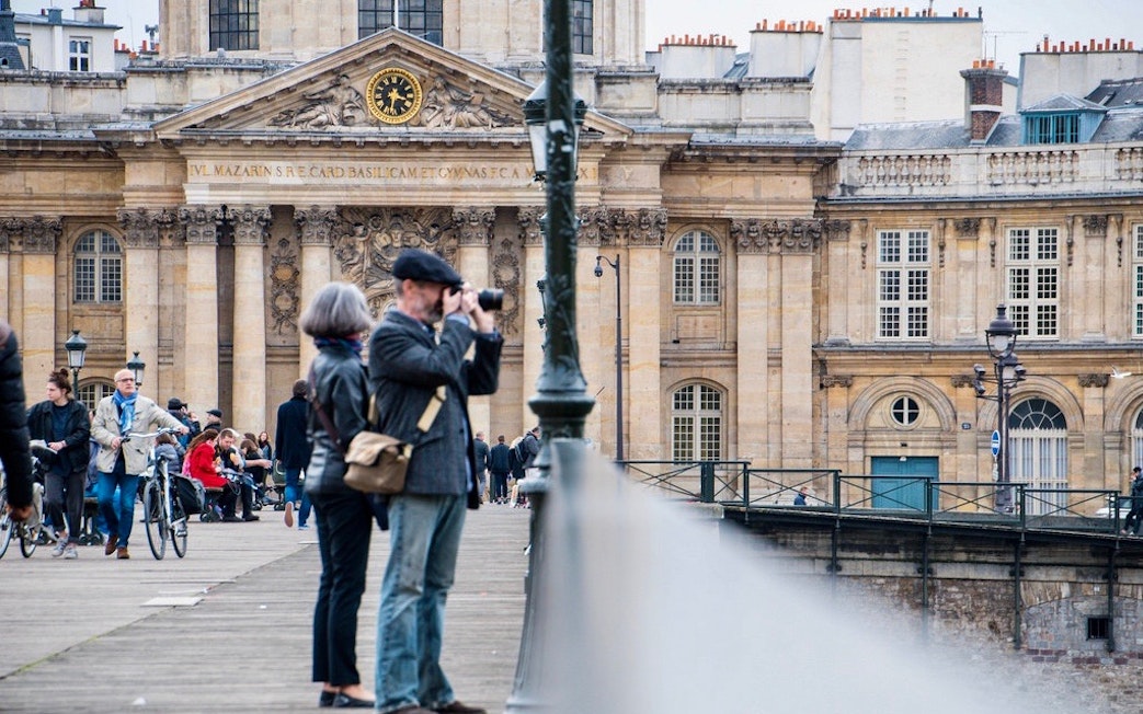 Tourists on a bridge near the Institut de France in Paris during a Seine River Cruise and City Tour.