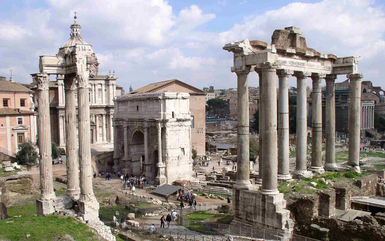 Roman Forum ruins with ancient columns and arches in Rome, Italy.