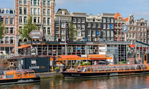 Amsterdam canal cruise boat navigating through historic downtown waterways.