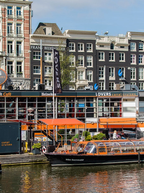Canal cruise boats docked in front of Van Gogh Café in Amsterdam downtown.