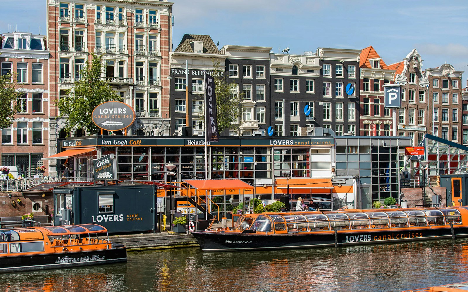 Canal cruise boats docked in front of Van Gogh Café in Amsterdam downtown.