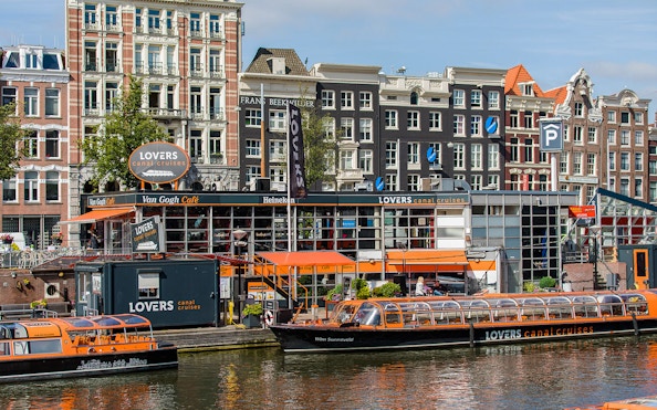 Canal cruise boats docked in front of Van Gogh Café in Amsterdam downtown.