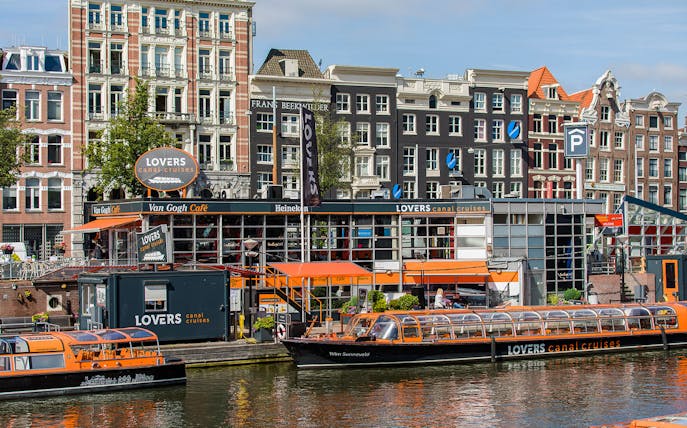 Canal cruise boats docked in front of Van Gogh Café in Amsterdam downtown.