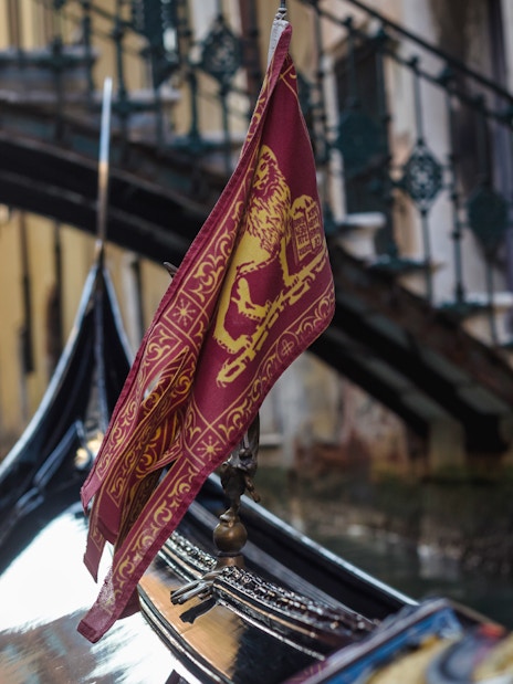 Gondola on a canal in Venice with a bridge in the background.