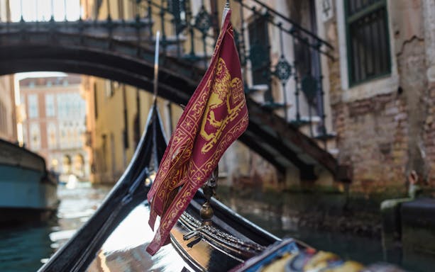 Gondola on a canal in Venice with a bridge in the background.