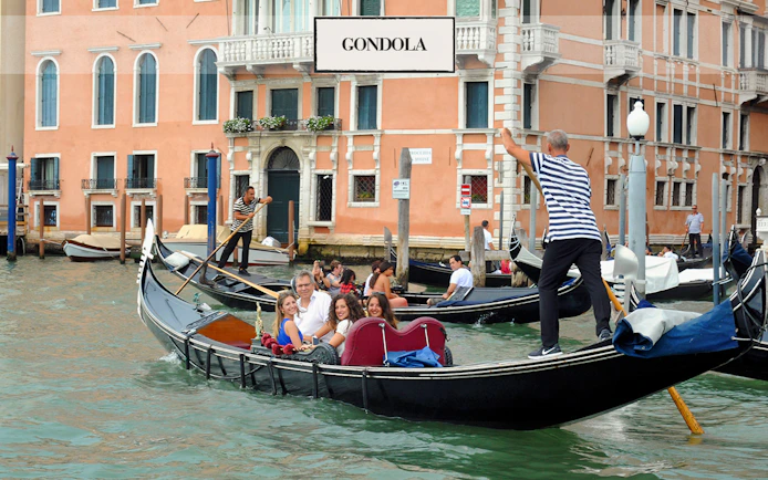 Gondola ride on a canal in Venice with tourists and gondoliers.