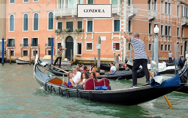 Gondola ride on a canal in Venice with tourists and gondoliers.
