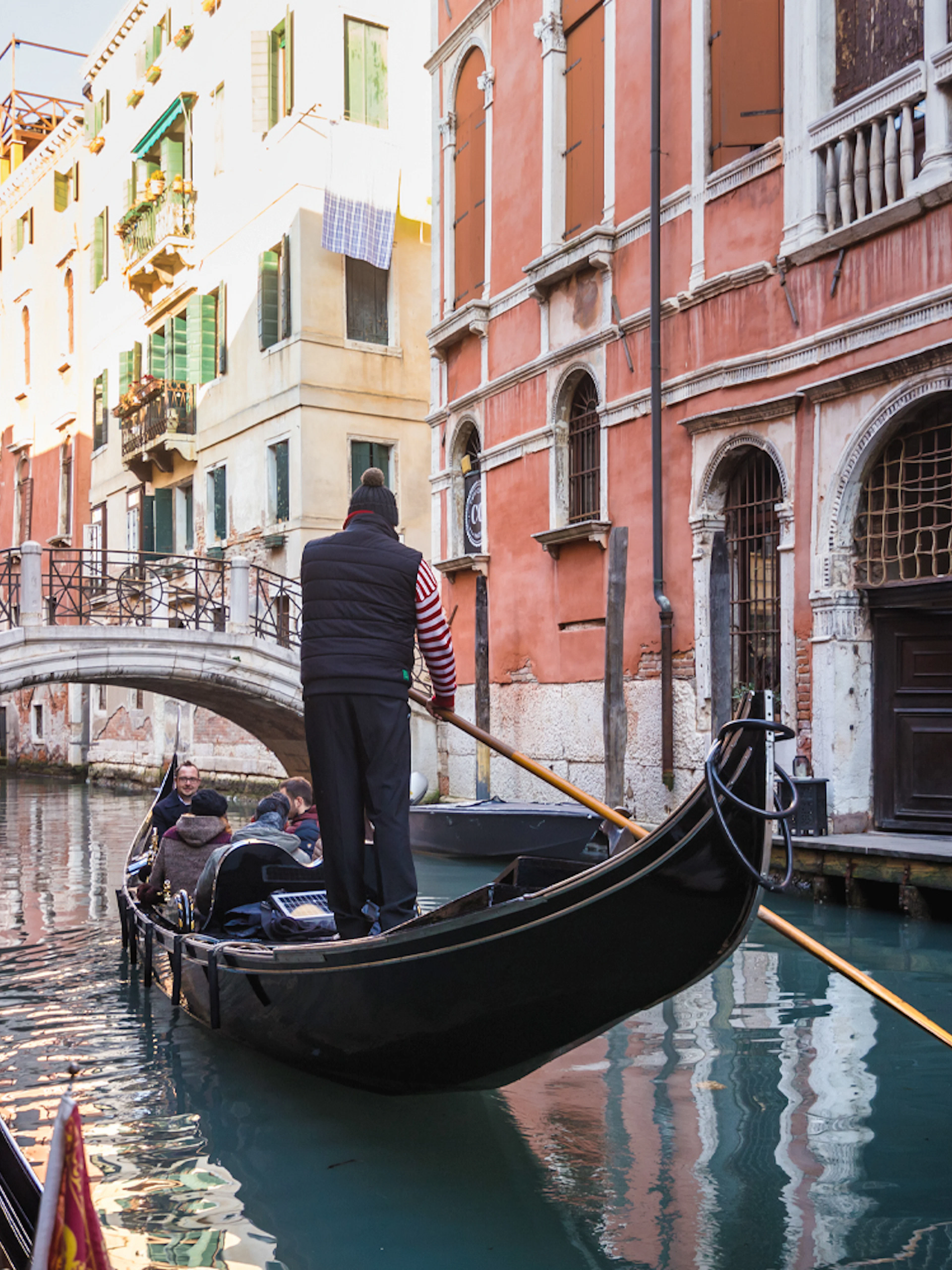 Gondola navigating a canal under a bridge in Venice during a guided walking tour.