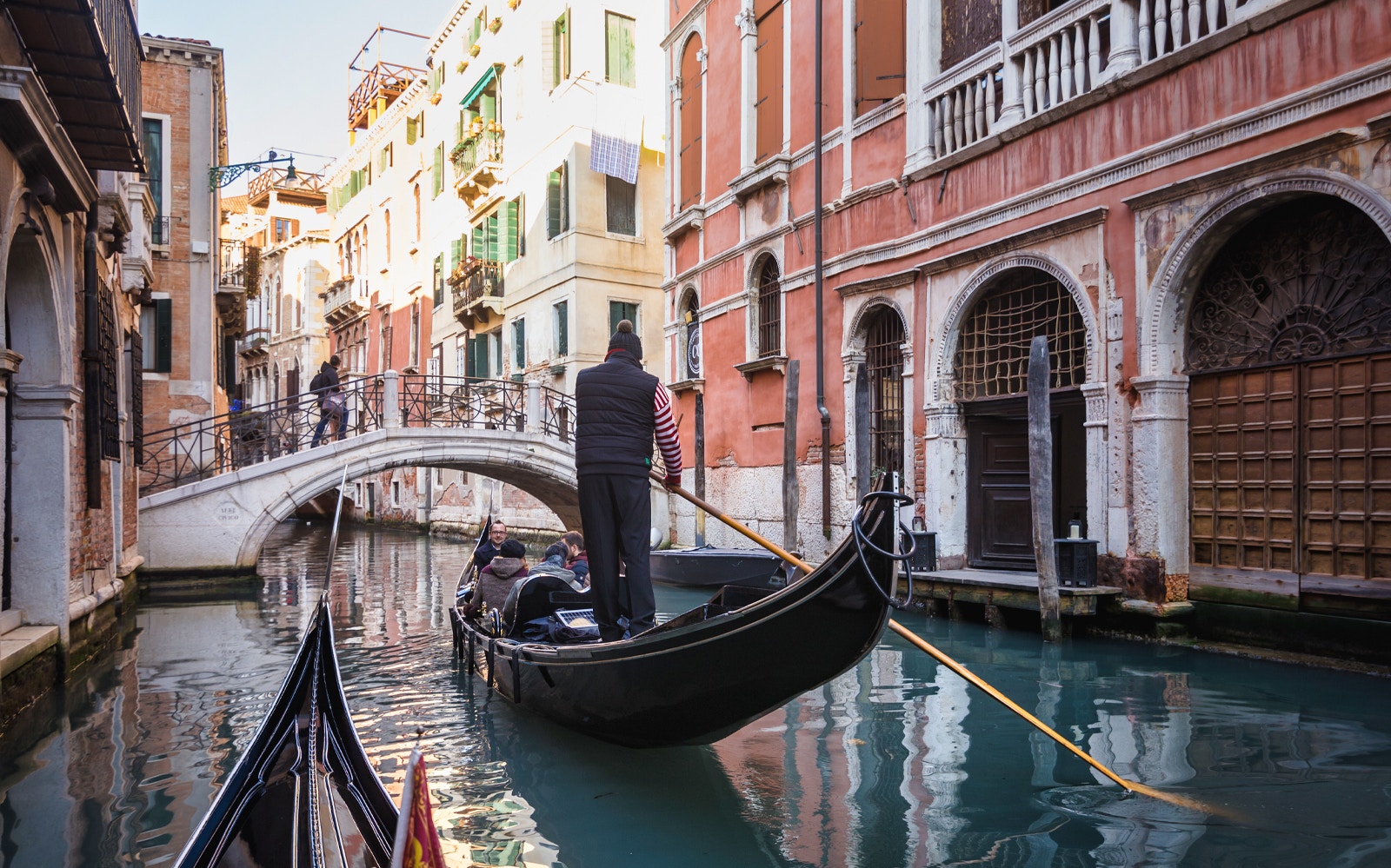 Gondola navigating a canal under a bridge in Venice during a guided walking tour.