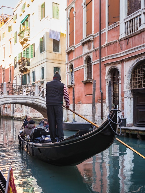 Gondola navigating a canal under a bridge in Venice during a guided walking tour.