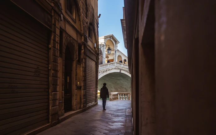Walking through a narrow alley towards the Rialto Bridge in Venice.