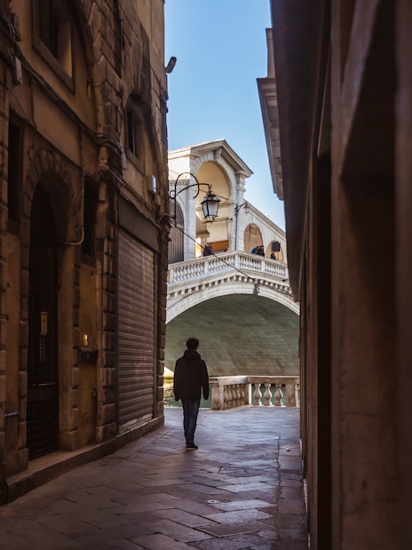 Walking through a narrow alley towards the Rialto Bridge in Venice.