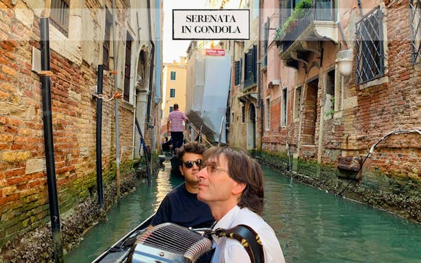 Gondola ride in Venice canal with musician playing accordion.