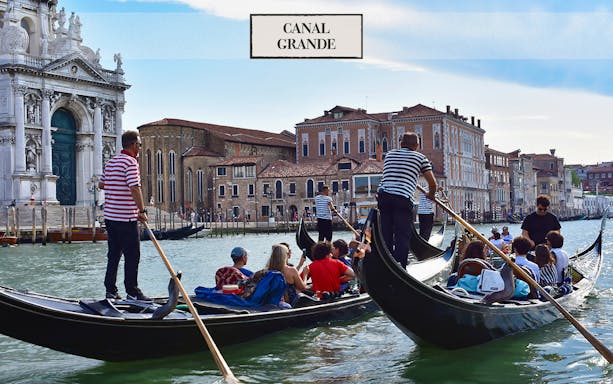 Gondolas on Venice's Grand Canal with passengers enjoying a serenade.
