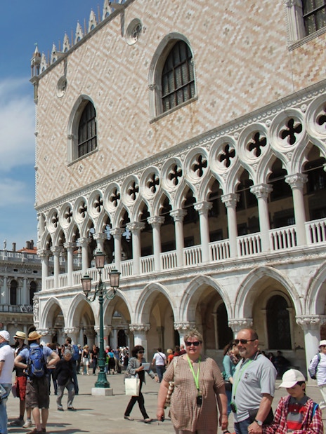 Crowd outside Doge's Palace in Venice with guidebooks, near St. Mark's Square.