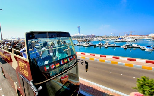 Open-top bus with tourists on Abu Dhabi waterfront during Big Bus sightseeing tour.