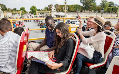 Tourists on Big Bus Paris tour, viewing map, with Eiffel Tower and Seine River in background.