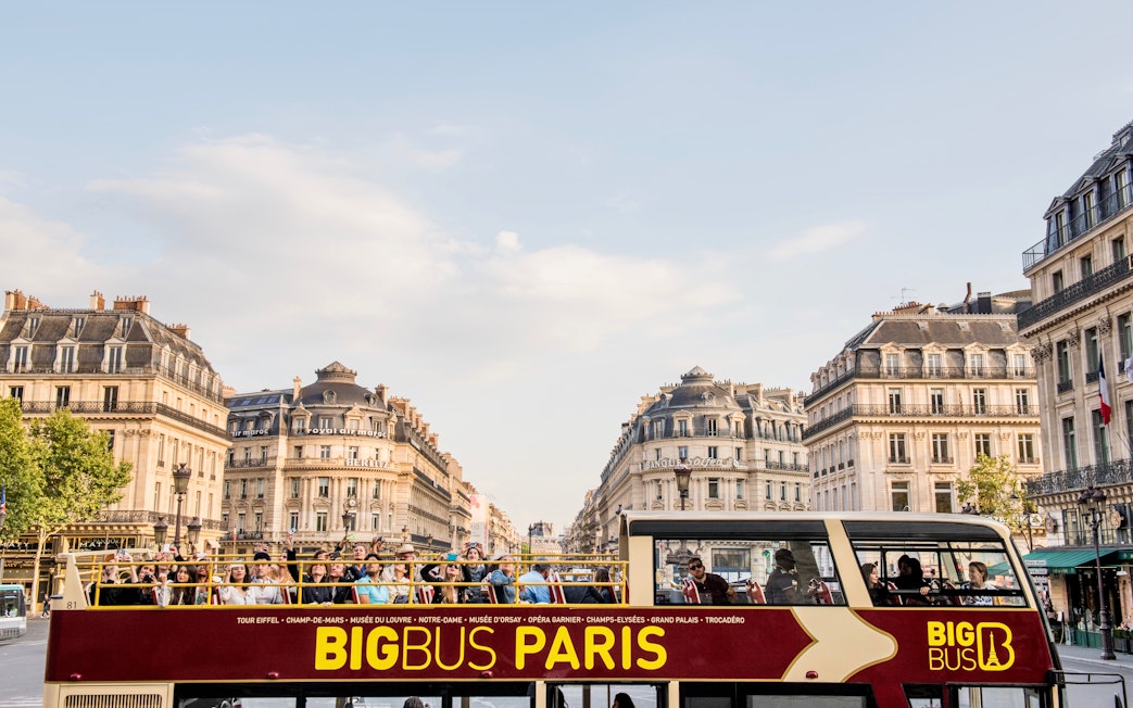 Tourists exploring Paris on a Hop-On Hop-Off bus with a view of Opera Garnier in the background