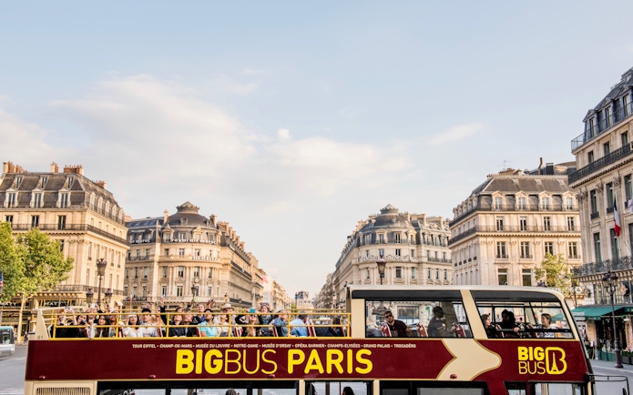 Tourists exploring Paris on a Hop-On Hop-Off bus with a view of Opera Garnier in the background