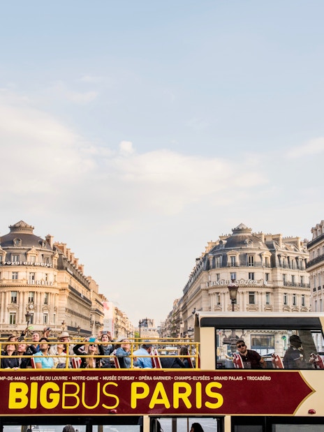 Tourists exploring Paris on a Hop-On Hop-Off bus with a view of Opera Garnier in the background