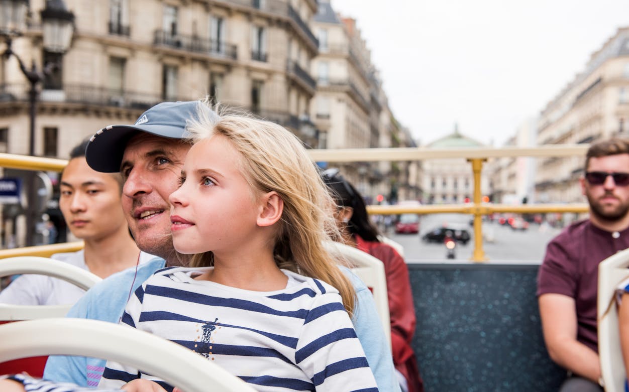 Tourists enjoying a view of Paris from an open-top bus on the BigBus Paris tour.