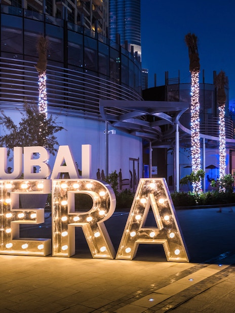 Dubai Opera House entrance illuminated at night with decorative lights.