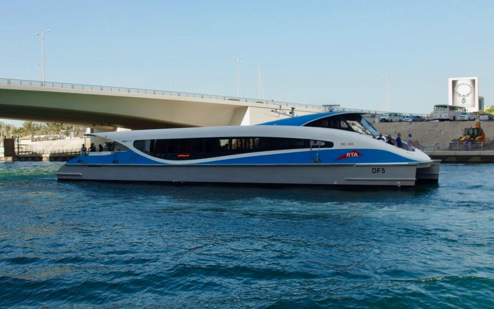 Dubai ferry cruising under a bridge from Ghubaiba to Dubai Marina.