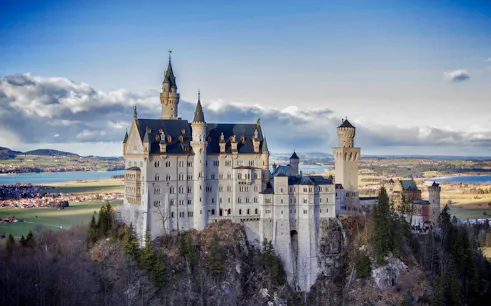 Neuschwanstein Castle in Bavaria, Germany, viewed from a distance with surrounding landscape.