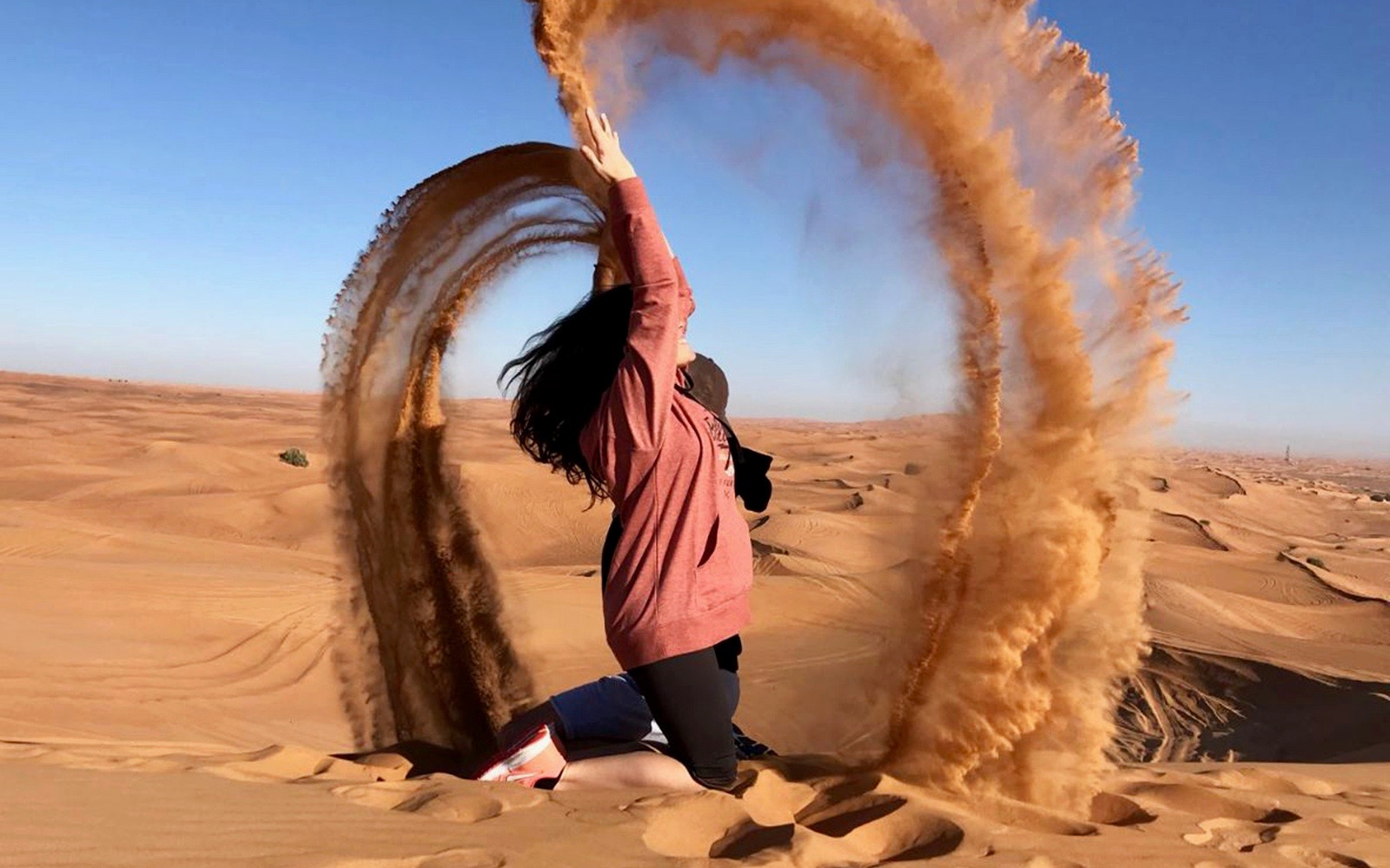 Person enjoying sandboarding in the desert during a morning safari.