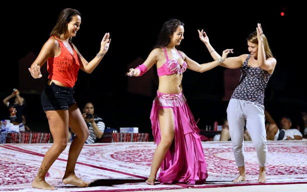 Women dancing during a desert BBQ dinner experience.
