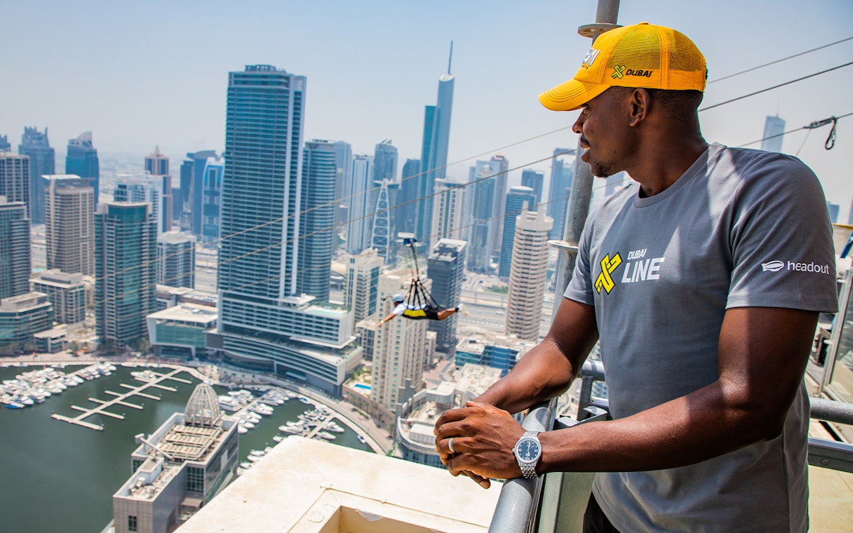 Zipliner over Dubai Marina with skyscrapers in the background, wearing a free XLine Dubai Marina T-shirt.