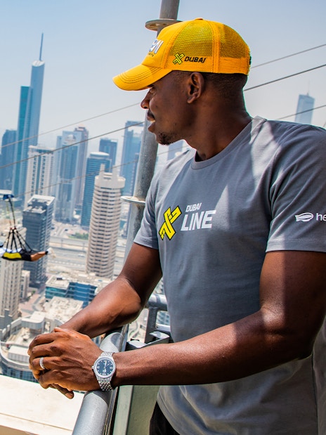 Zipliner over Dubai Marina with skyscrapers in the background, wearing a free XLine Dubai Marina T-shirt.