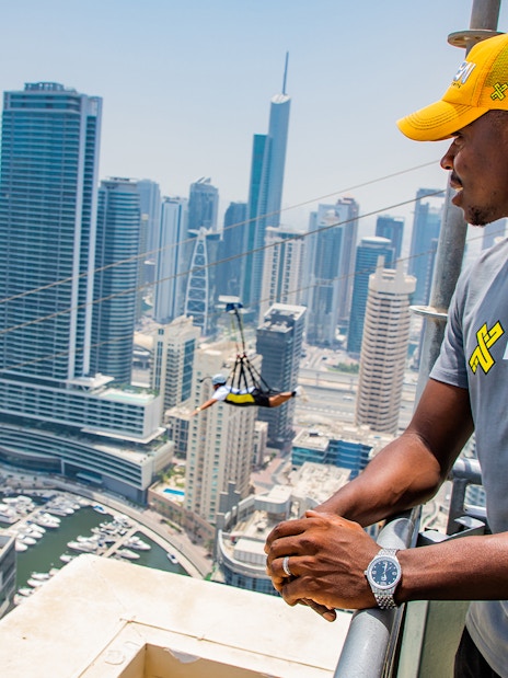 Zipliner over Dubai Marina with skyscrapers in the background, wearing a free XLine Dubai Marina T-shirt.