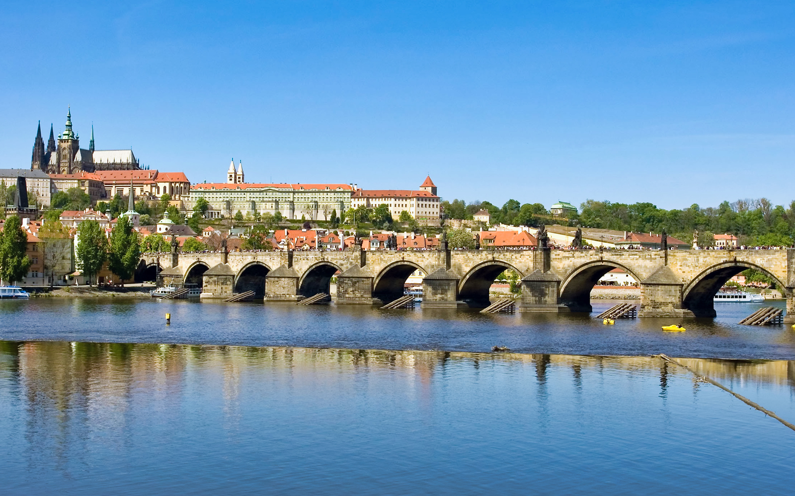 Prague Castle and Charles Bridge over Vltava River on a sunny day.