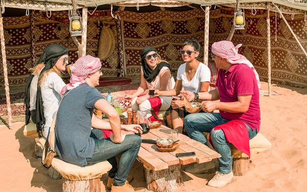 Group enjoying Bedouin breakfast in desert tent during Heritage Falconry & Morning Nature Safari.