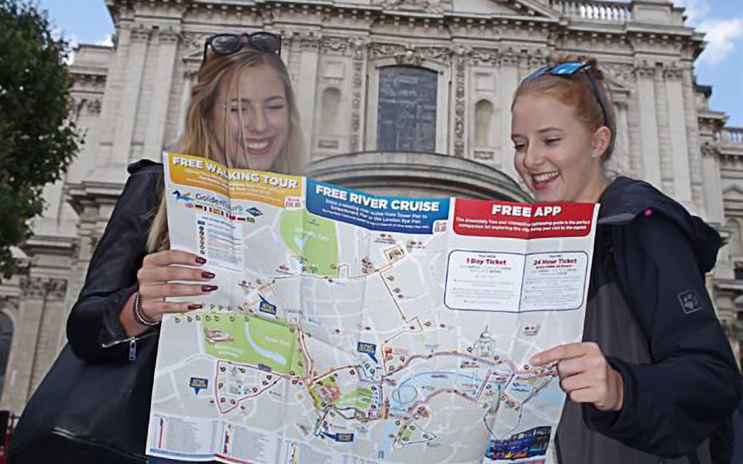 Two people holding a map in front of a historic building in London.