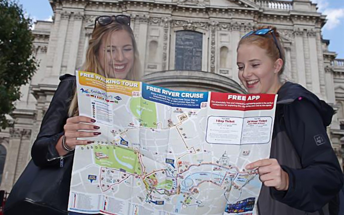 Two people holding a map in front of a historic building in London.