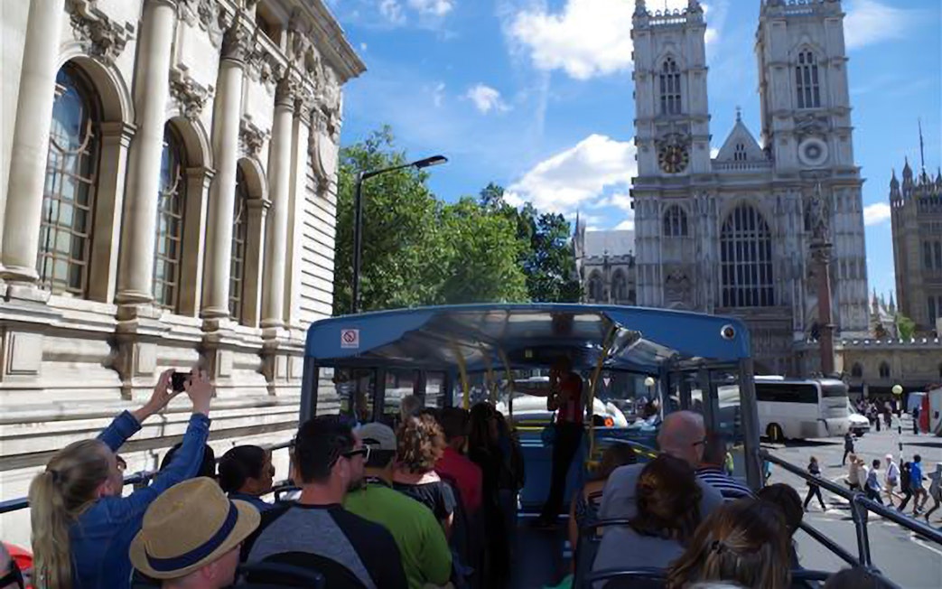 Open-top bus tour passing Westminster Abbey in London.