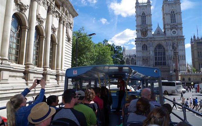 Open-top bus tour passing Westminster Abbey in London.