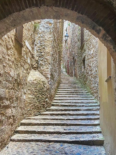Stone archway and narrow staircase in Girona, Spain, part of the Girona & Figueres day trip.