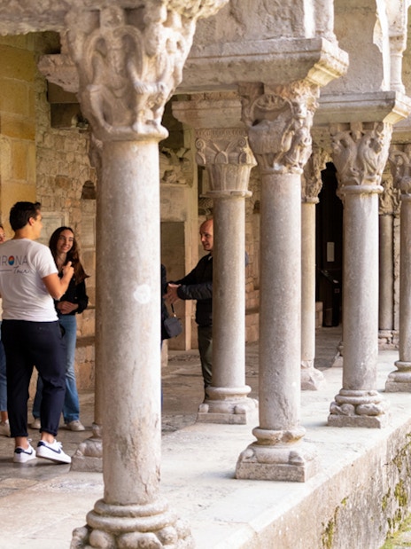 Visitors exploring the cloister of a historic building in Girona, Spain.