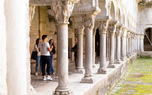 Visitors exploring the cloister of a historic building in Girona, Spain.