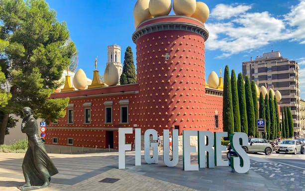 Figueres Dali Museum exterior with large egg sculptures and nearby statue.