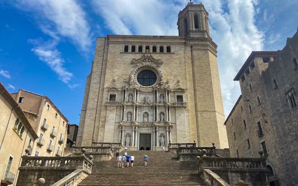 Girona Cathedral facade with tourists on steps, part of Girona & Figueres day trip from Barcelona.