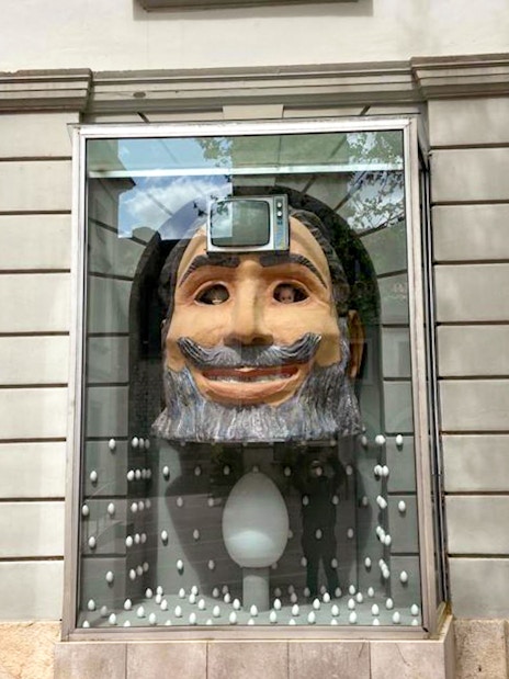 Display window with a large head sculpture and TV at Dalí Museum, Figueres, on Girona & Figueres day trip.