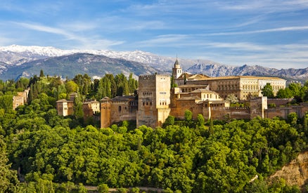 Alhambra palace and Generalife gardens in Granada, Spain, with Sierra Nevada mountains in the background.