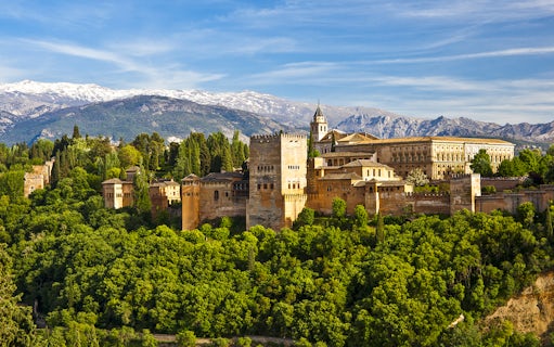 Alhambra palace and Generalife gardens in Granada, Spain, with Sierra Nevada mountains in the background.