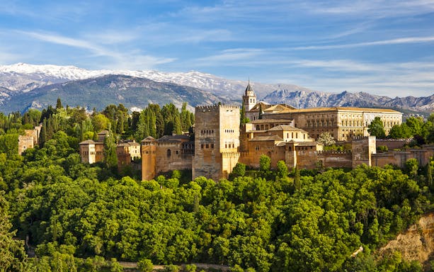 Alhambra palace and Generalife gardens in Granada, Spain, with Sierra Nevada mountains in the background.