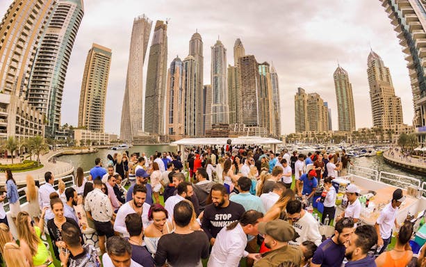 Crowd enjoying brunch on Lotus Mega Yacht with Dubai Marina skyline.
